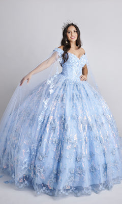 A woman stands against a plain background wearing the Nina Canacci Q104 long Quinceanera dress in light blue, featuring an off-the-shoulder design, floral details, a flowing skirt, and accessorized with a large jeweled crown.