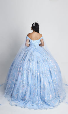 A woman in the Nina Canacci Q104 Long Quinceanera Dress, a light blue off-the-shoulder ball gown with floral patterns and a tiara, stands facing away against a plain light background.