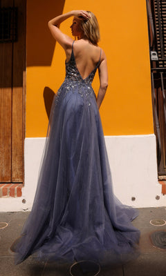 A woman stands with her back and shoulders elegantly exposed in the Deep V-Back Long Tulle A-Line Prom Dress Q1391, a sleeveless, floor-length gown adorned with embroidered flowers, facing a bright yellow wall.