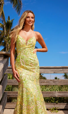 A woman in the Sequin-Floral Long Prom Gown: Nox Anabel Q1540 stands outdoors by a wooden railing, with palm trees and a blue sky in the background.