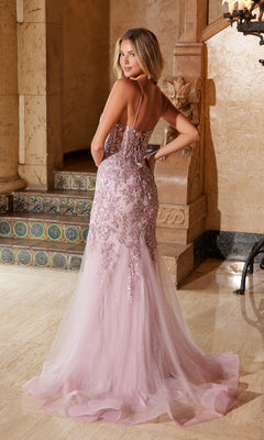 A woman models the Nox Anabel Q1541—an elegant, floor-length light pink prom dress with floral embroidery, a lace-up back, and a shimmering train. This stunning gown is perfect for prom.