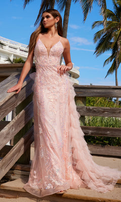 A woman in the Nox Anabel Q1542 Ruffled Long Beaded Prom Dress stands by a wooden railing outdoors, palm trees gently swaying behind her.
