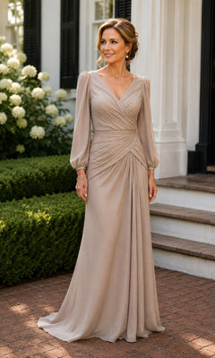 A woman wears the Sheer Sleeve Ruched Chiffon Formal Dress: Rina Di Montella R101, a champagne-colored, floor-length chiffon evening gown with a V-neckline, sheer long sleeves, and a ruched bodice.