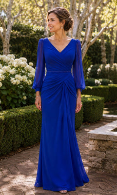 A woman wears a royal Sheer Sleeve Ruched Chiffon Formal Dress: Rina Di Montella R101, a floor-length dress featuring sheer long sleeves, a V-neckline, and a ruched waist.