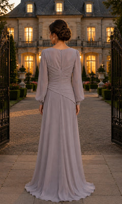Back view of a woman wearing a mauve Tie-Waist Chiffon Long Formal Dress: Rina Di Montella R103, a modest floor-length, long-sleeved gown, standing in front of a grand estate.