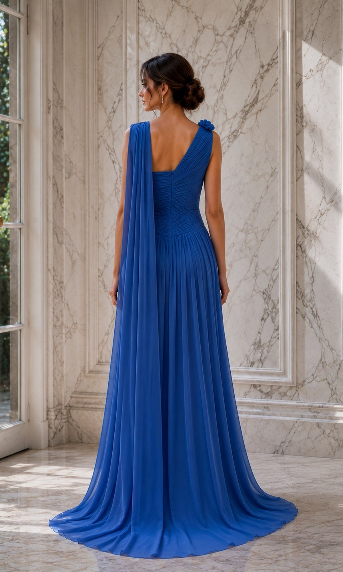 A woman seen from the back wearing a royal blue One Shoulder Cape Long Formal Dress: Rina Di Montella R110, featuring a one-shoulder pleated bodice and a trailing chiffon cape.