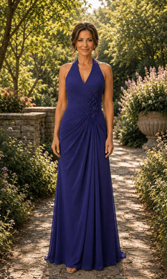 A woman wearing a deep purple Rina Di Montella R112 Halter Ruched Chiffon Formal Dress, a floor-length gown with side ruching and floral detailing on the hip.