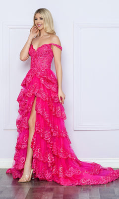 A woman wearing the Nox Anabel Off-the-Shoulder Lace Prom Dress R1299 with a ruffled skirt, floral embroidery, thigh-high slit, and clear heels poses against a light-colored wall.