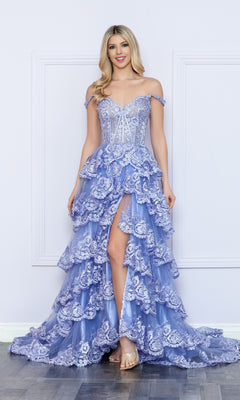 A woman poses by a white wall wearing the Nox Anabel Off-the-Shoulder Lace Prom Dress R1299, showcasing lavender ruffled layers, a sheer corset bodice, front slit, and clear high-heeled sandals.