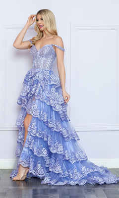 A woman stands indoors in the Nox Anabel Off-the-Shoulder Lace Prom Dress R1299, featuring a lavender hue, layered design, sheer corset bodice, high-low hem, and clear high heels.