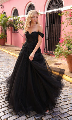 A woman in the Off-the-Shoulder Long Tulle Prom Ball Gown R1303 stands on a cobblestone street beside a pink building with arched windows and potted plants.