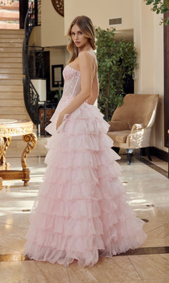 A woman wearing the Nox Anabel R1688 Strapless Ruffled Prom Ball Gown stands indoors on marble flooring, looking over her shoulder near a staircase and a beige armchair.