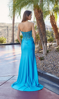 A woman stands outdoors facing away, wearing the Nox Anabel R1690—a strapless sweetheart prom gown in bright blue, floor-length with a sequin-embroidered corset bodice.