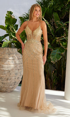 A woman smiles in front of greenery, wearing the Nox Anabel R1715 Lace-Up Beaded Long Prom Dress, a fitted, sleeveless gold-beige gown with metallic details and a sheer overlay.