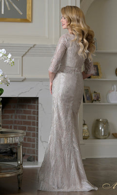 A woman with long wavy blonde hair stands facing away in an elegant room, wearing the floor-length Rina Di Montella RD3530 silver embroidered mesh formal dress.