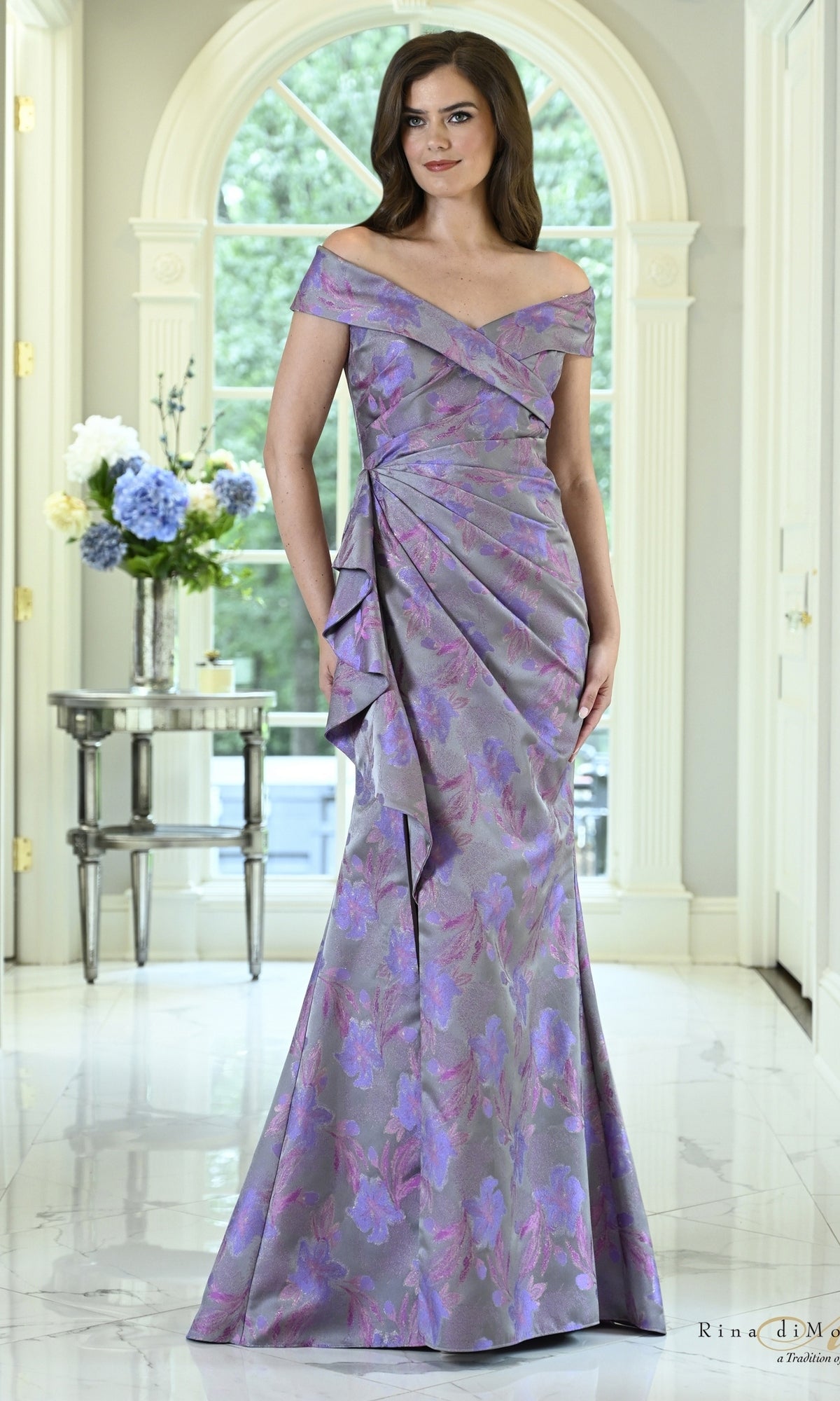 Rina Di Montella RD3617 floral ruffle mermaid formal dress in grey and purple, featuring an off-the-shoulder neckline and draped ruffle detailing at the hip.