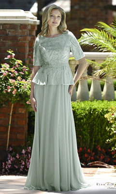 A woman wearing a Beaded Lace Peplum Long Formal Dress: Rina Di Montella RD3642 in seaglass, featuring a floor-length modest evening gown with a beaded lace bodice and a peplum waist.