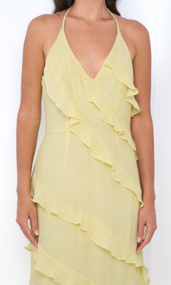 A woman wears the Remi by Velvi V-Neck Halter Ruffled Long Prom Dress in light yellow, standing against a white background.