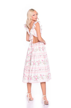 A woman models the Pink Floral Casual Midi Dress: Rosette, featuring ruffled straps and an open back, paired with white heels against a white backdrop.