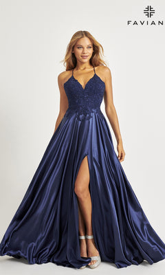 A woman wears the Faviana Lace-Bodice Long A-Line Prom Dress, featuring an elegant navy satin skirt with a high slit and an embroidered lace bodice. The "FAVIAN" logo appears in the top right corner.