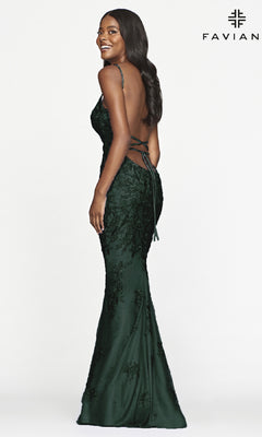 Woman in a dark green Faviana Lace Embroidery Long Backless Prom Dress stands sideways, smiling. The fitted gown has thin straps and lace embroidery. "FAVIAN" logo appears in the top right corner.