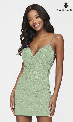 A woman wears the V-Neck Short Backless Homecoming Dress by Faviana—light green, fitted, with lace embroidery and thin straps—standing and smiling against a plain background with the Faviana logo; perfect for any special occasion.