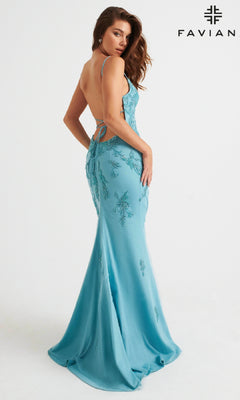 Woman wearing a light pink, floor-length prom dress with a strappy back by Faviana, posing against a plain white background. "FAVIANA" and the logo appear in the top right, suggesting the elegance of this designer gown.