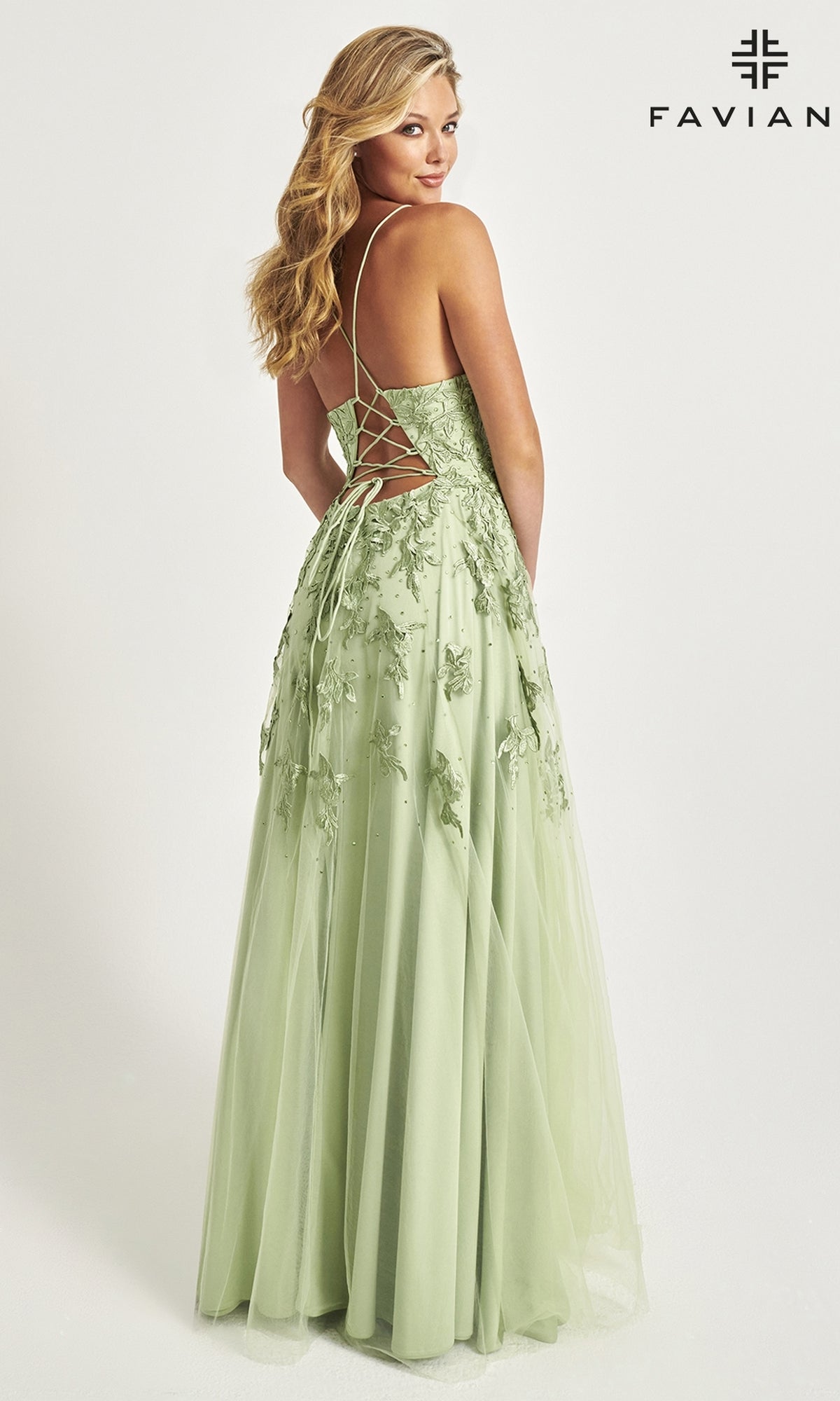 A woman faces away in a light green Faviana Embroidered A-Line Long Prom Dress with 3-D floral embroidery and a lace-up back; 