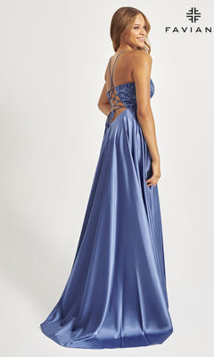 A woman in the Faviana Beaded-Bodice Long Prom Dress S10870, featuring blue satin, a beaded v-neck bodice with thin straps, an a-line silhouette, lace-up back, fitted bodice, and flowing skirt, stands facing away looking over her shoulder.
