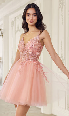 A woman stands indoors, smiling in the Short Babydoll Homecoming Dress: CLSF047—an A-line party dress with a sleeveless embroidered lace bodice and a knee-length pink tulle skirt.