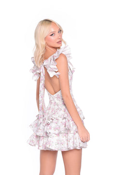 A blonde woman models the Seraphine Floral Print Ruffled Backless Sundress, showcasing its sleeveless design, ruffle skirt, open back, and bow detail against a white background.