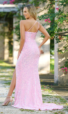 Woman outdoors in the Velvi One-Shoulder Long Sequin Prom Dress Stardust, a sparkly pink floor-length gown with a thigh-high slit, posing with one hand on her hip and facing away from the camera.