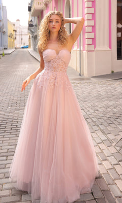 A woman in the Strapless Sheer-Waist Long Prom Ball Gown T1326 with pale pink tulle and lace details stands on a cobblestone street lined with colorful buildings.