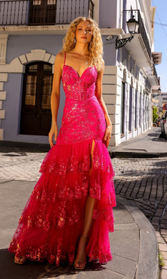 A woman stands on a cobblestone street in the Sequin Long Ruffled Mermaid Prom Dress T1337, a bright pink sparkly gown with tiers and a thigh-high slit, set against white and blue buildings.