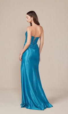 A woman in the Nox Anabel T1489 Strapless Lace-Up Long Prom Gown, a fitted metallic blue dress with a lace-up back, stands facing away from the camera against a plain beige background.