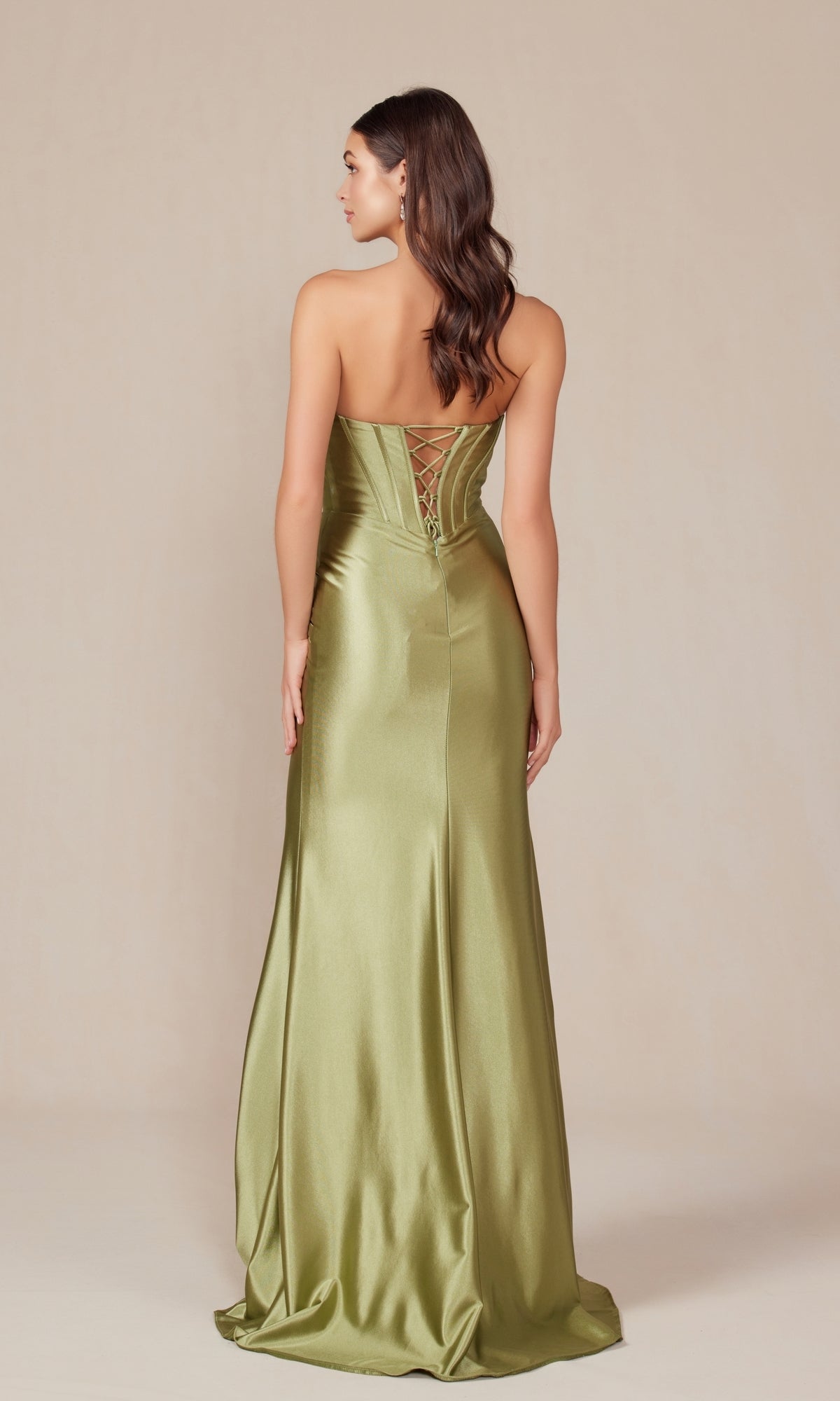 A woman faces away from the camera, wearing the Nox Anabel T1500— a strapless long corset prom dress with an olive green satin floor-length skirt and a lace-up back— set against a plain background.