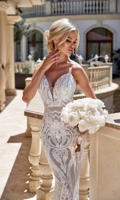 A woman in the Tina Holly T19280 long white sequin wedding gown holds a bouquet of white roses on a sunlit terrace.