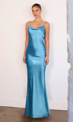 A woman poses against a plain wall in the Astee T2000 Cowl-Back Sexy Long Prom Dress, a fitted, floor-length satin gown with thin straps in light blue.