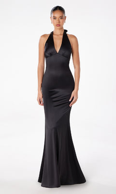 A woman stands facing forward against a white background, modeling the Bow-Back Long Satin Halter Prom Dress: Astee T2001 in black—a sleeveless, floor-length satin dress perfect for formal occasions.