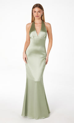 A woman stands against a white background wearing the Bow-Back Long Satin Halter Prom Dress: Astee T2001, featuring a light green hue, fitted bodice, flared hem, and elegant halter neckline.