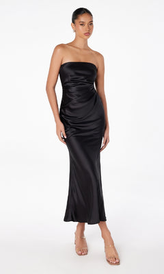 A woman wearing the Strapless Long Satin Maxi Prom Dress: Astee T2006 and clear high-heeled sandals stands against a plain white background.