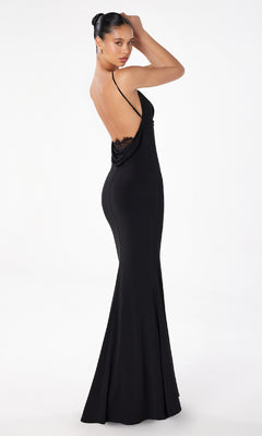 A woman models the Astee T2008 Cowl Open-Back Long Prom Dress, a form-fitting black gown with thin spaghetti straps and a low open back, posing against a plain white background.