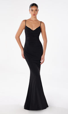 A woman stands against a white background wearing the Astee T2008 Cowl Open-Back Long Prom Dress, a fitted, floor-length black formal gown with spaghetti straps and a slight mermaid silhouette.