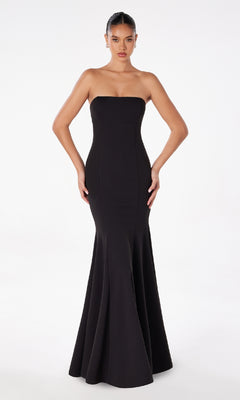 A woman stands against a white background wearing the Lace-Up Strapless Long Prom Dress: Astee T2010—an elegant, form-fitting black evening gown with a flared hem.