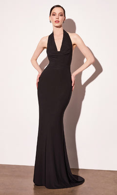 Woman modeling a long black prom dress with a halter cowl neckline standing in front of a white wall.