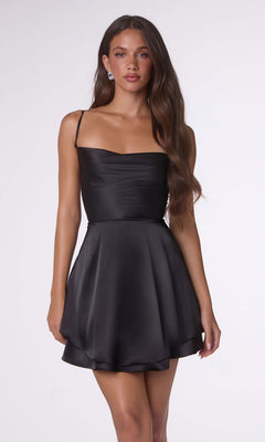 A woman stands against a plain light background wearing the Amoris T616 short black homecoming dress, featuring thin straps and an open back.