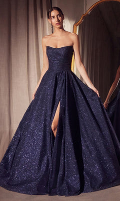 A woman in the Strapless Long A-Line Glitter Prom Dress: Amoris T701—a dark blue, strapless gown with a high slit—stands indoors near a mirror and beige curtains.