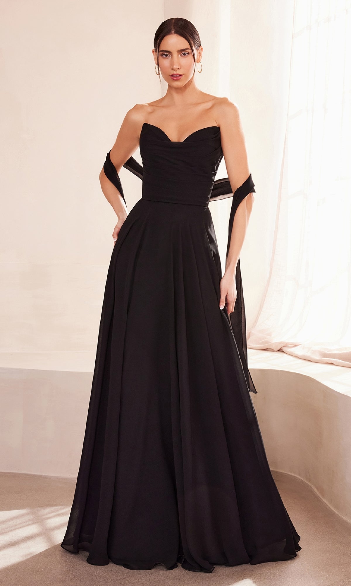 A woman stands indoors wearing the Strapless Long Chiffon Prom Dress: Amoris T703, featuring a sweetheart neckline and a matching black shawl draped around her arms.