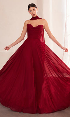 A woman is indoors wearing the Strapless Long Chiffon Prom Dress: Amoris T703 in deep red—a formal, affordable strapless gown with a full skirt and a matching sheer scarf around her neck.