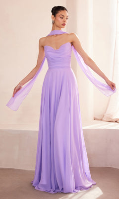A woman stands in a softly lit room wearing the Strapless Long Chiffon Prom Dress: Amoris T703—a floor-length lavender gown featuring a corset bodice and a flowing chiffon scarf draped around her neck and arms.